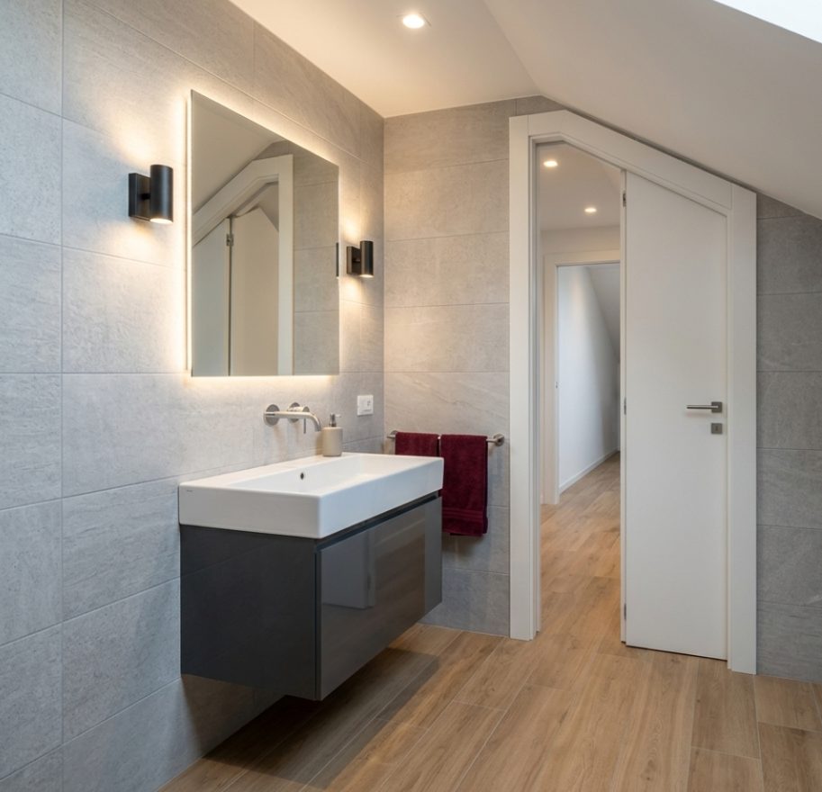 Bagno moderno ristrutturato con rivestimenti in gres e pavimento effetto legno
